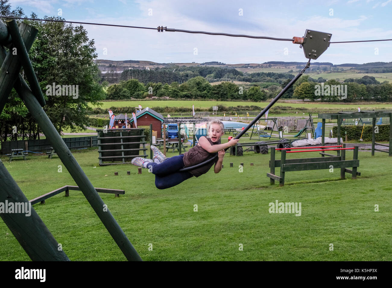 Ragazza divertirsi basculante in filo di zip in gioco adventure park di Denny, SCOZIA Foto Stock