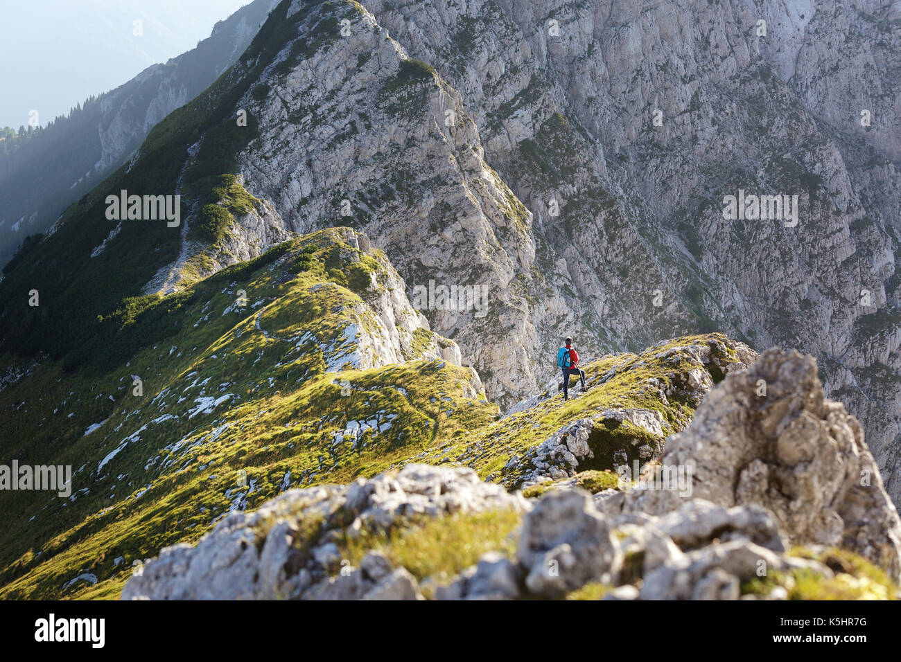 Woman in Red jacket, con bastoni per escursioni e passeggiate zaino fino a un punto di vista su Kladivo, Karavanke, Slovenia. Foto Stock
