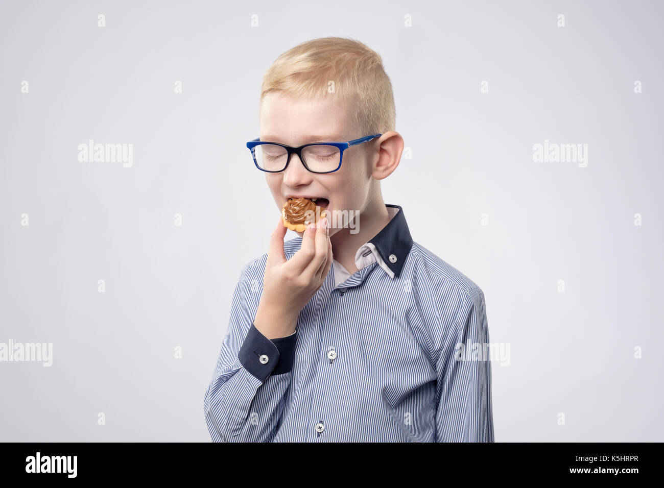 Bello piccolo ragazzo di mangiare la crema Cup cake. Foto Stock