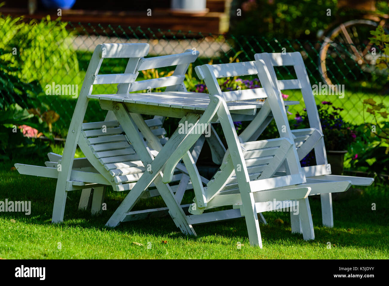 Legno bianco mobili da esterno lungo un giardino recinto su un prato. Foto Stock