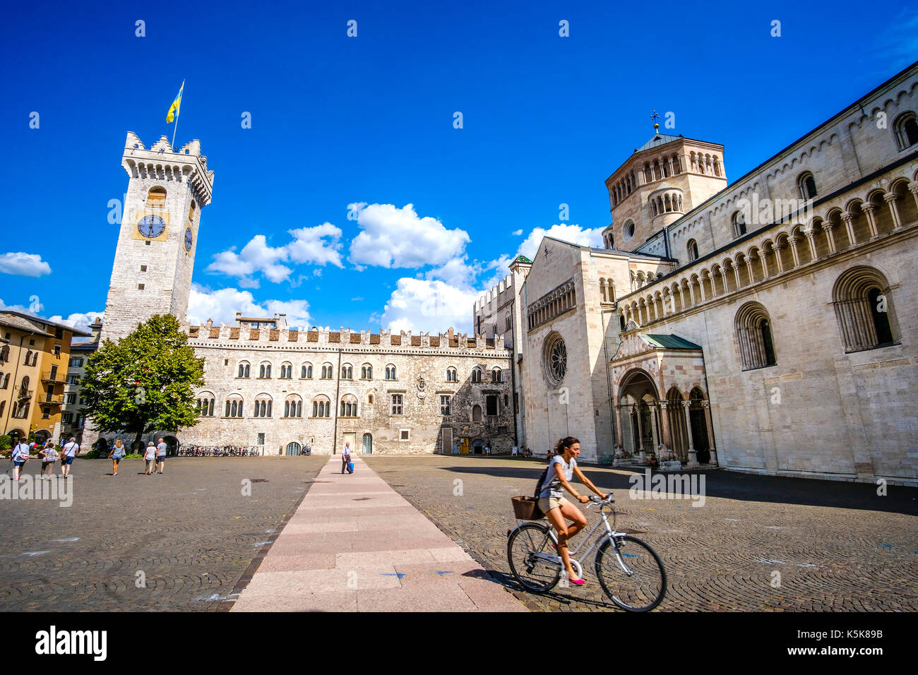 Trento, Italia, 14 ago 2017 - una giovane donna andare in bicicletta nel mezzo della piazza duomo di Trento. Viaggiare in bicicletta in Italia, viaggio culturale in Italia Foto Stock