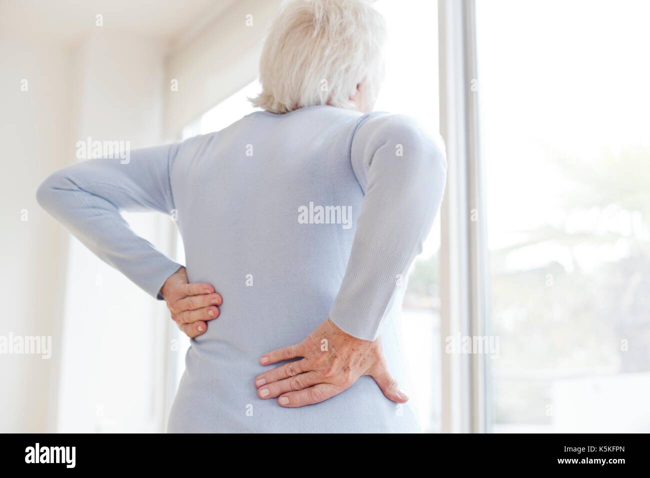 Senior sfregamento donna mal di schiena. Foto Stock