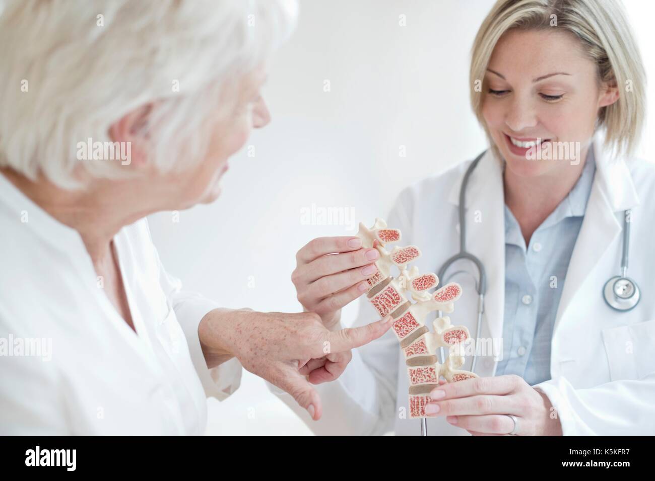 Medico donna che mostra il paziente modello anatomico della colonna vertebrale umana. Foto Stock