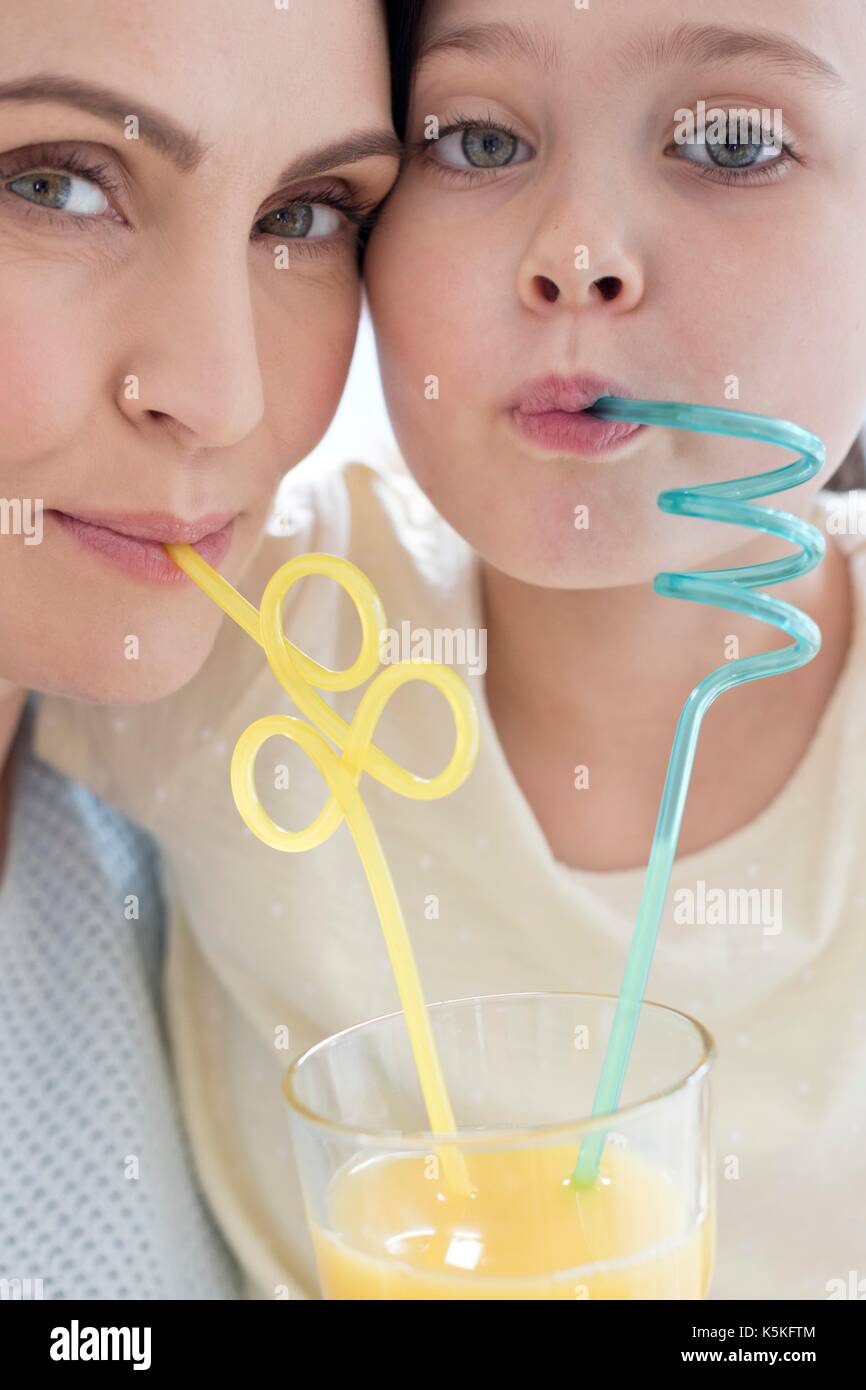 Madre e figlia di bere attraverso bendy cannucce, ritratto. Foto Stock