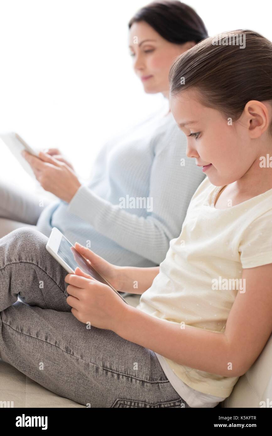 Madre e figlia sul divano con digital compresse. Foto Stock