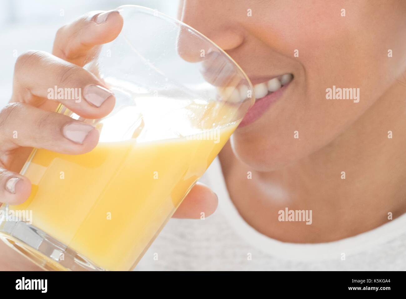 Metà donna adulta di bere un bicchiere di succo di arancia, ritratto. Foto Stock