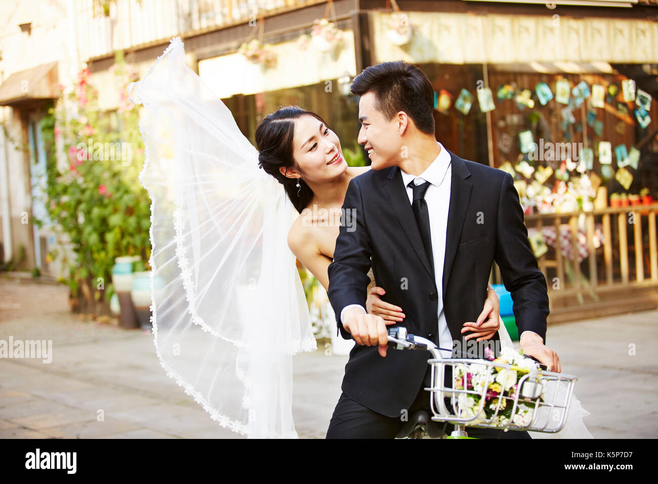 Asian romantica coppia di novelli sposi per divertirsi in sella ad una bicicletta insieme. Foto Stock