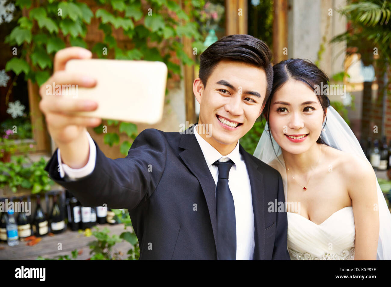 Giovani asiatici sposa e lo sposo prendendo un selfie tramite cellulare. Foto Stock