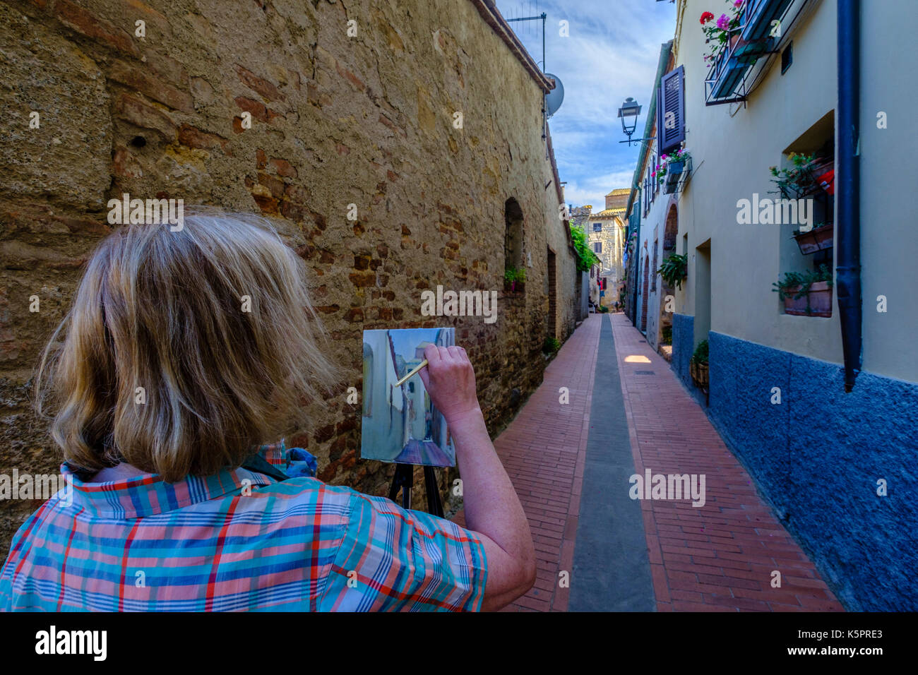 Un pittore è la pittura arte tra le vecchie case in una piccola strada in città medievale Foto Stock