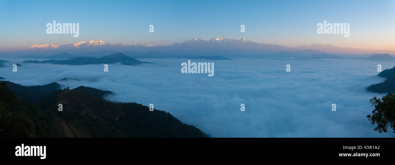 Vista panoramica di lontani himalayan picchi di montagna incandescente rosso da alba di luce sopra un mare ondeggiante di nuvole visto da bandipur, Nepal Foto Stock