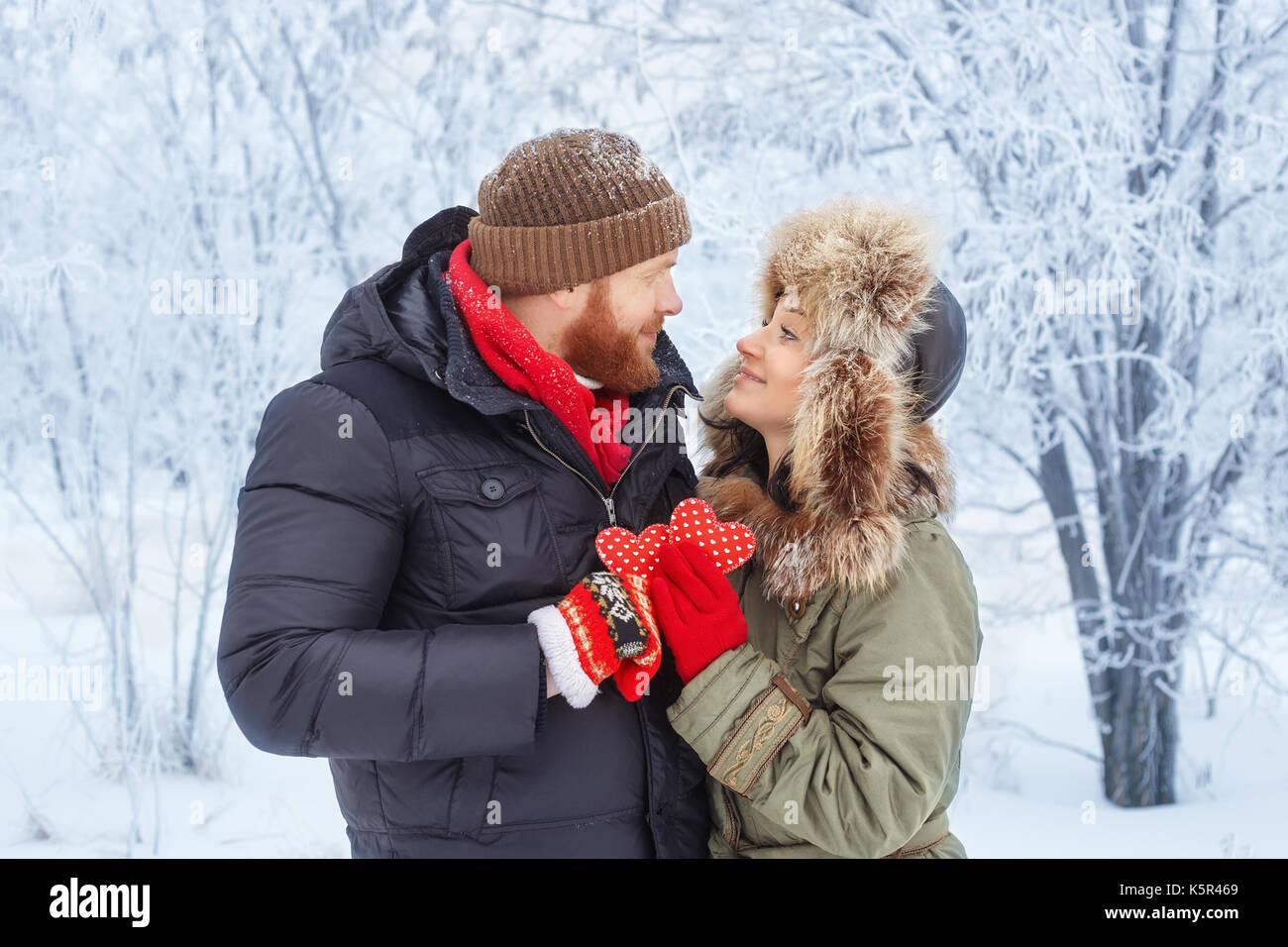 Una storia di amore in inverno foresta con cuori rossi. giovane coppia romantica outdoor. Coppia felice in inverno abiti azienda cuore rosso. il giorno di San Valentino e Foto Stock