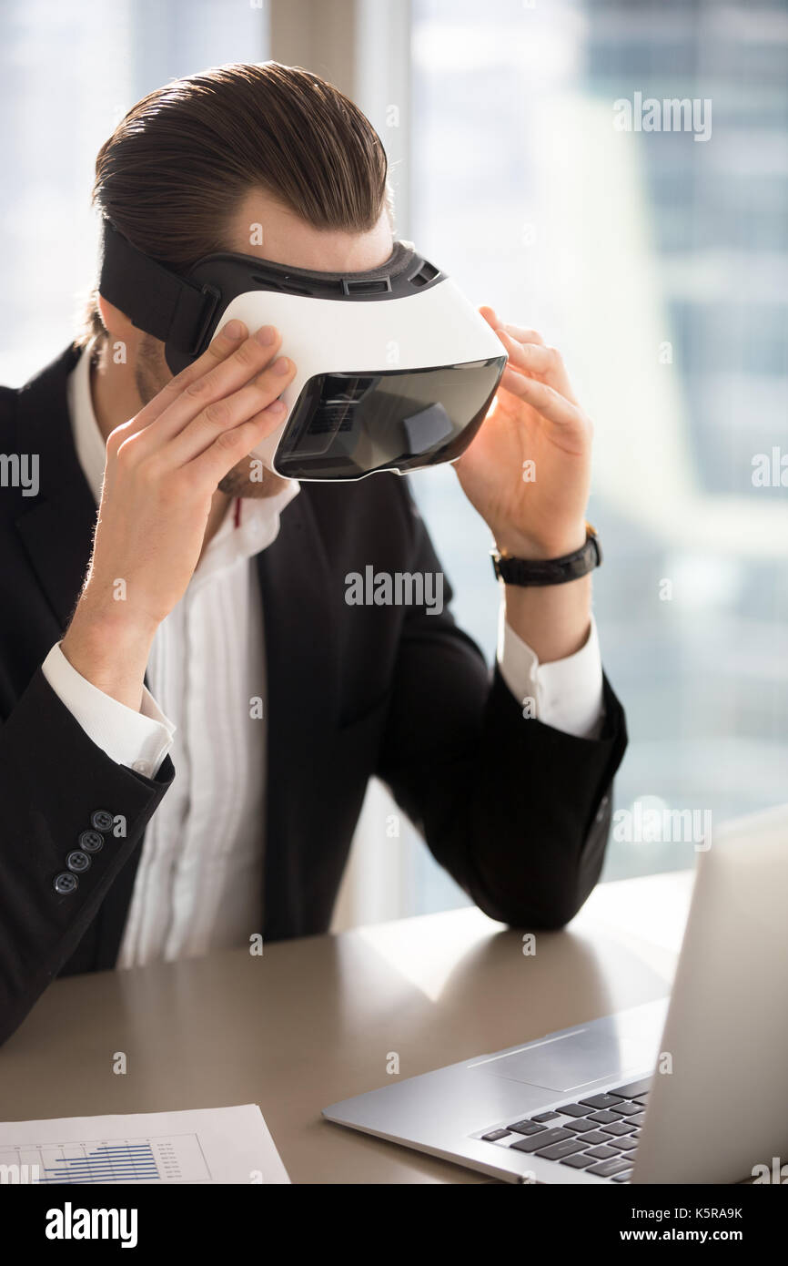 Imprenditore indossa occhiali vr guardando lo schermo del notebook. Foto Stock