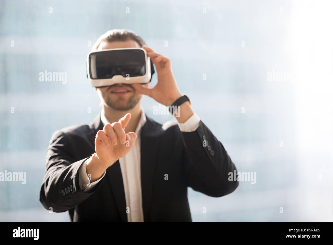Imprenditore sorridente in occhiali vr puntare il dito nell'aria. Foto Stock