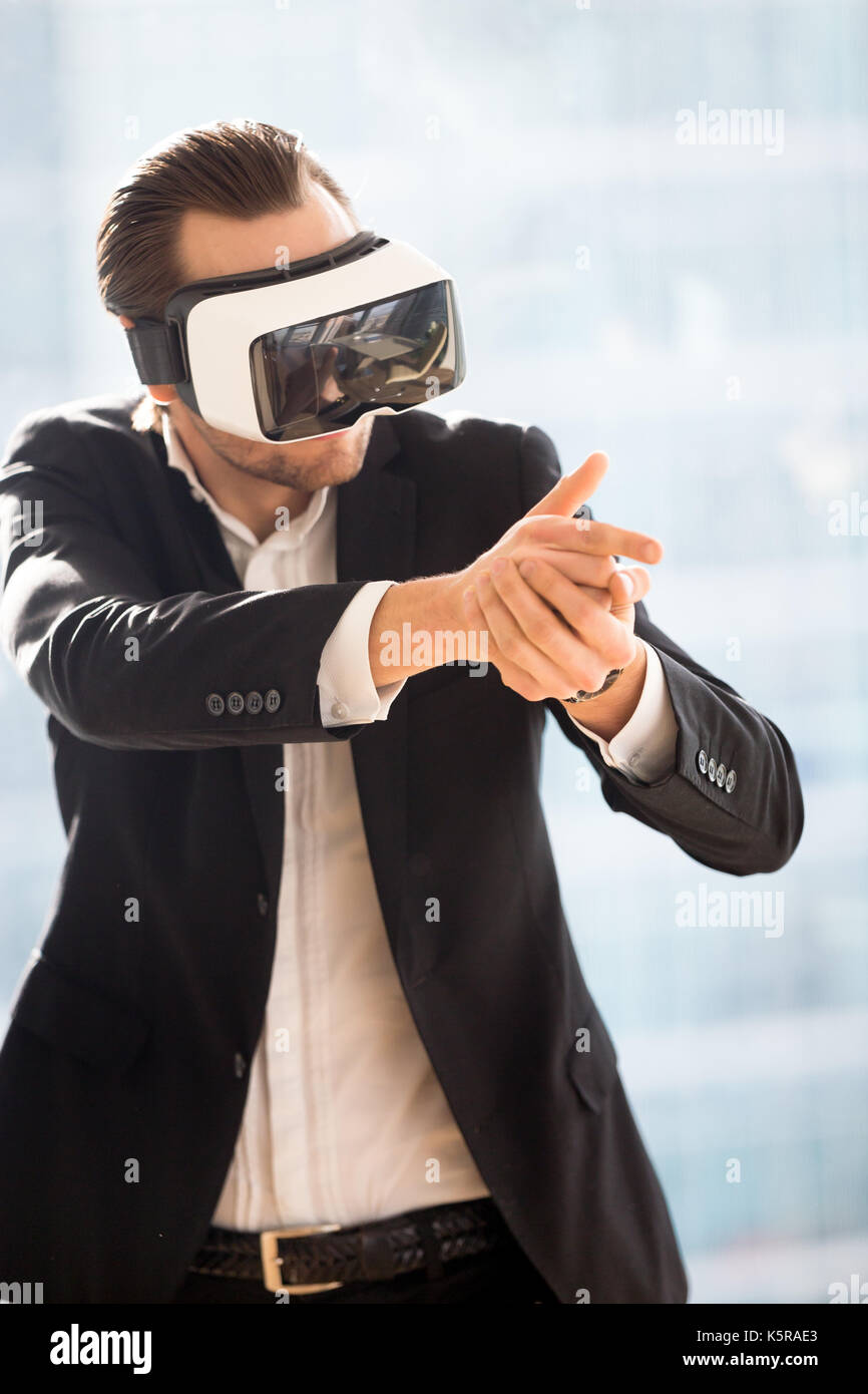 Imprenditore in vr auricolare con pistola a dito la riproduzione di gioco sparatutto. Foto Stock