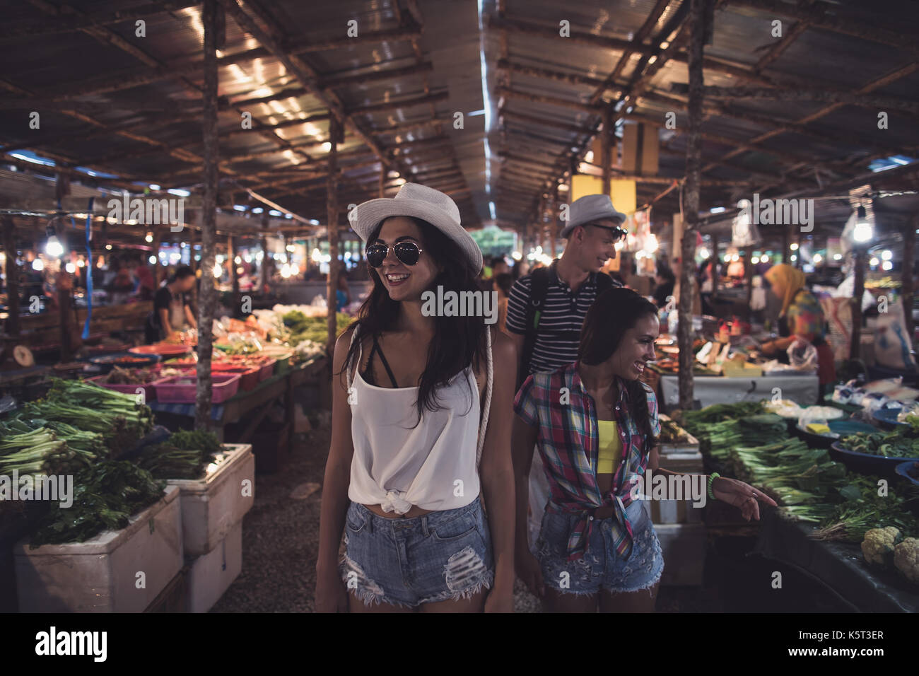 I turisti a piedi tra le righe sulla tropicale mercato esotici ai giovani la scelta di frutta fresca e verdura in asian bazaar Foto Stock