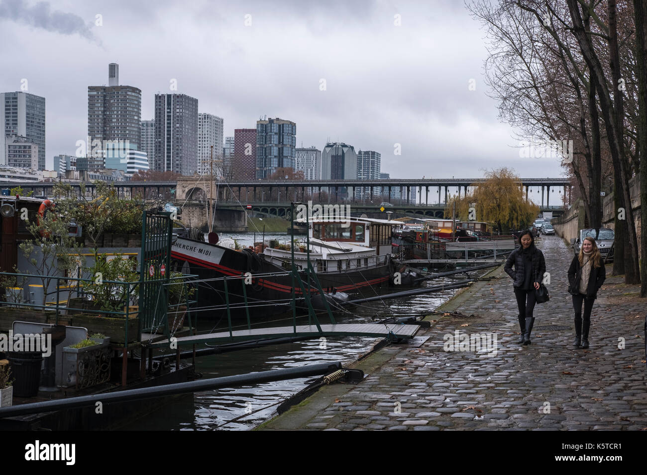 Due giovani donne a piedi lungo la Senna a Parigi, Francia, con il Bir Hakeim bridge in background su un giorno d'inverno. Foto Stock
