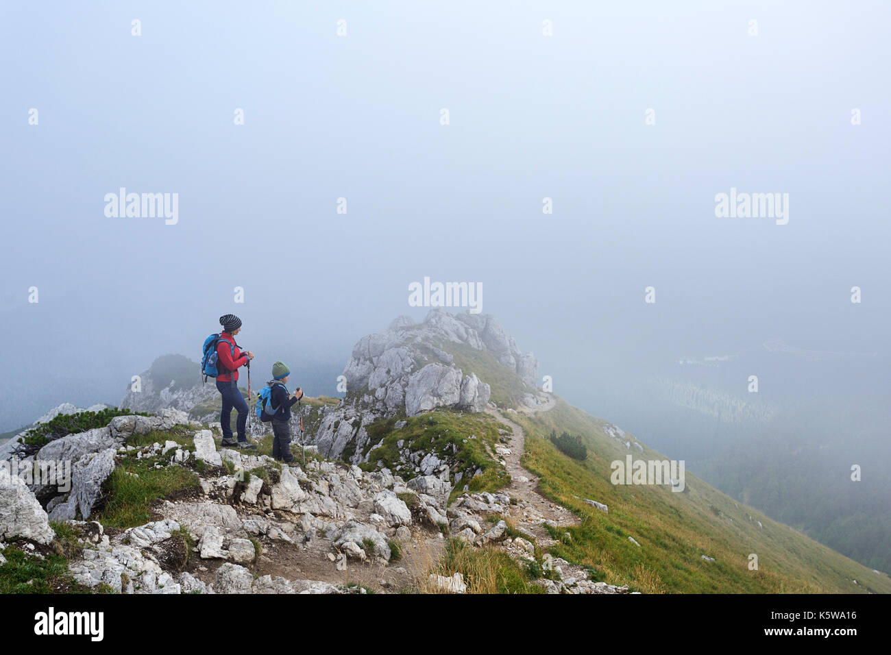 La madre e il figlio in piedi, escursionismo sulla cima della montagna coperta di nebbia, Visevnik, sulle Alpi Giulie, Slovenia. Foto Stock