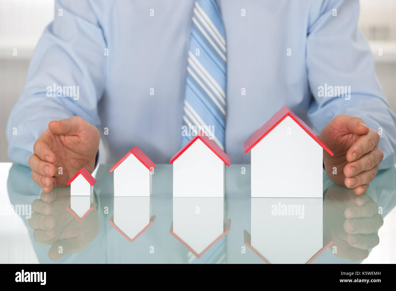 Close-up di imprenditore la protezione di modelli della casa in ufficio Foto Stock