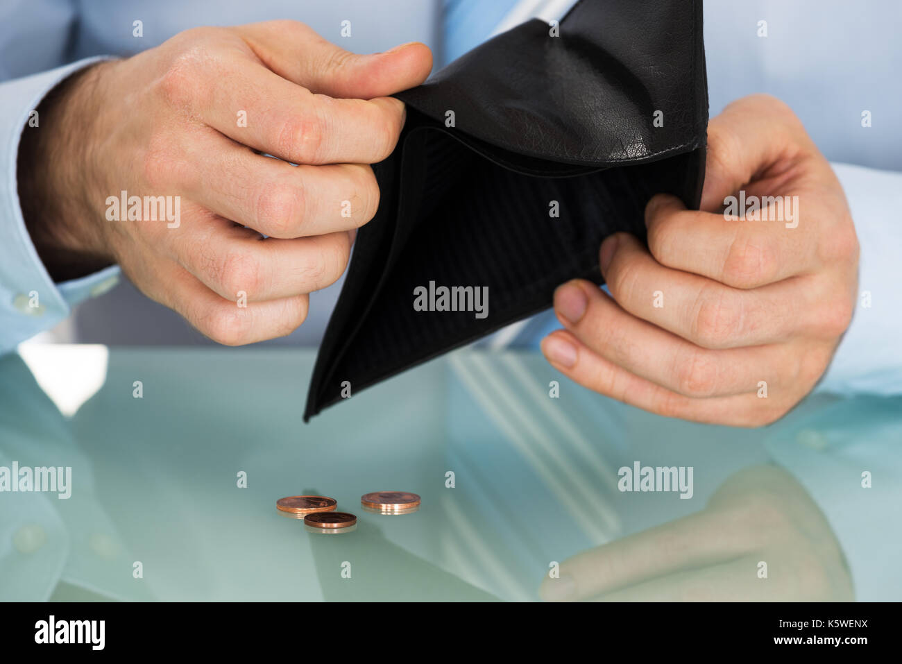 Imprenditore controllando il suo portafoglio con le monete sulla scrivania Foto Stock