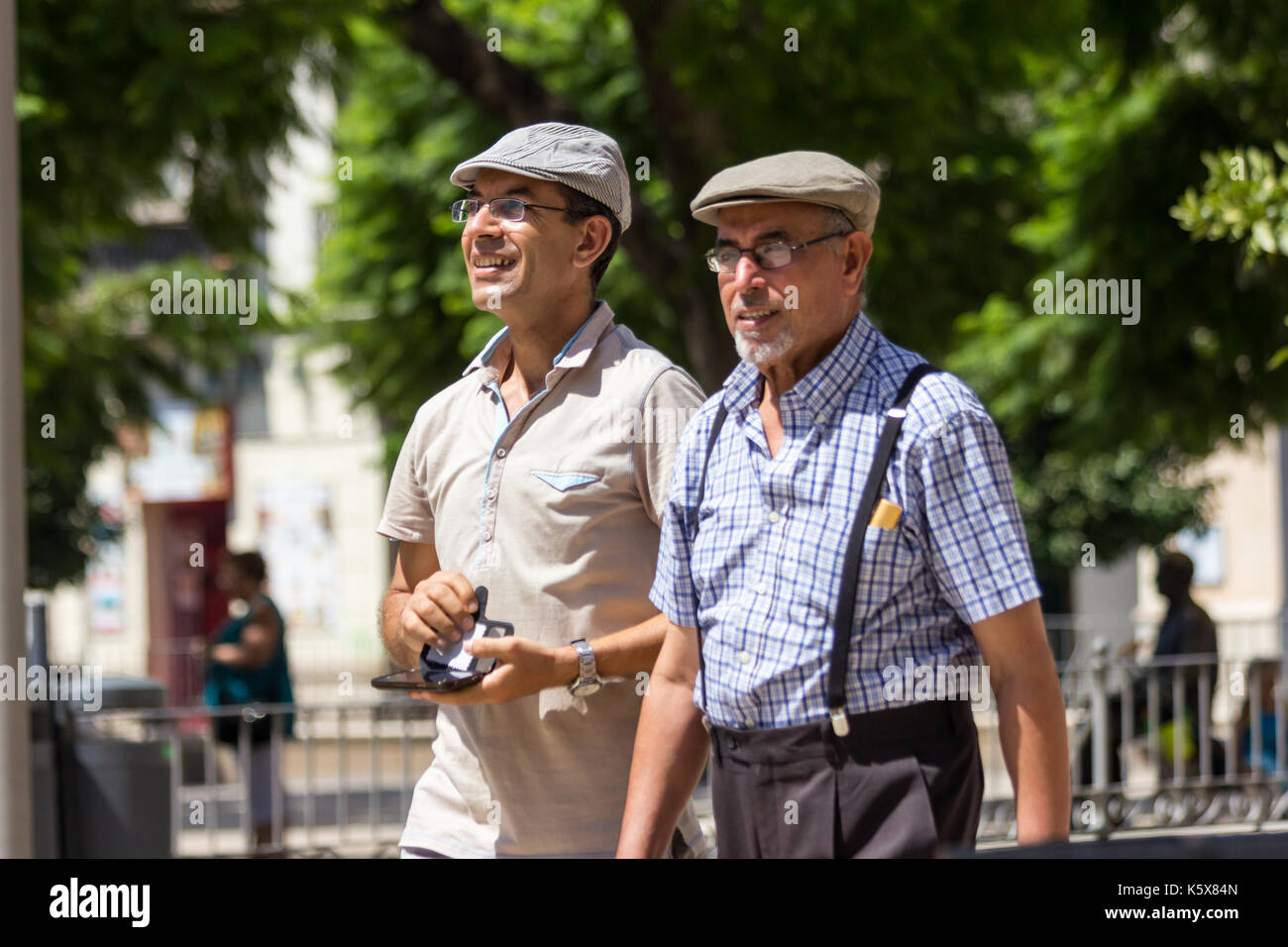 Padre figlio snd camminando in Malaga, Spagna indossando tappi piatti Foto Stock