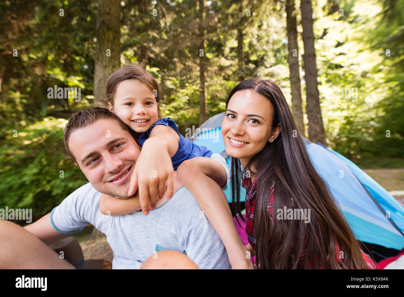 Giovane e bella famiglia con figlia camping nella foresta. Foto Stock