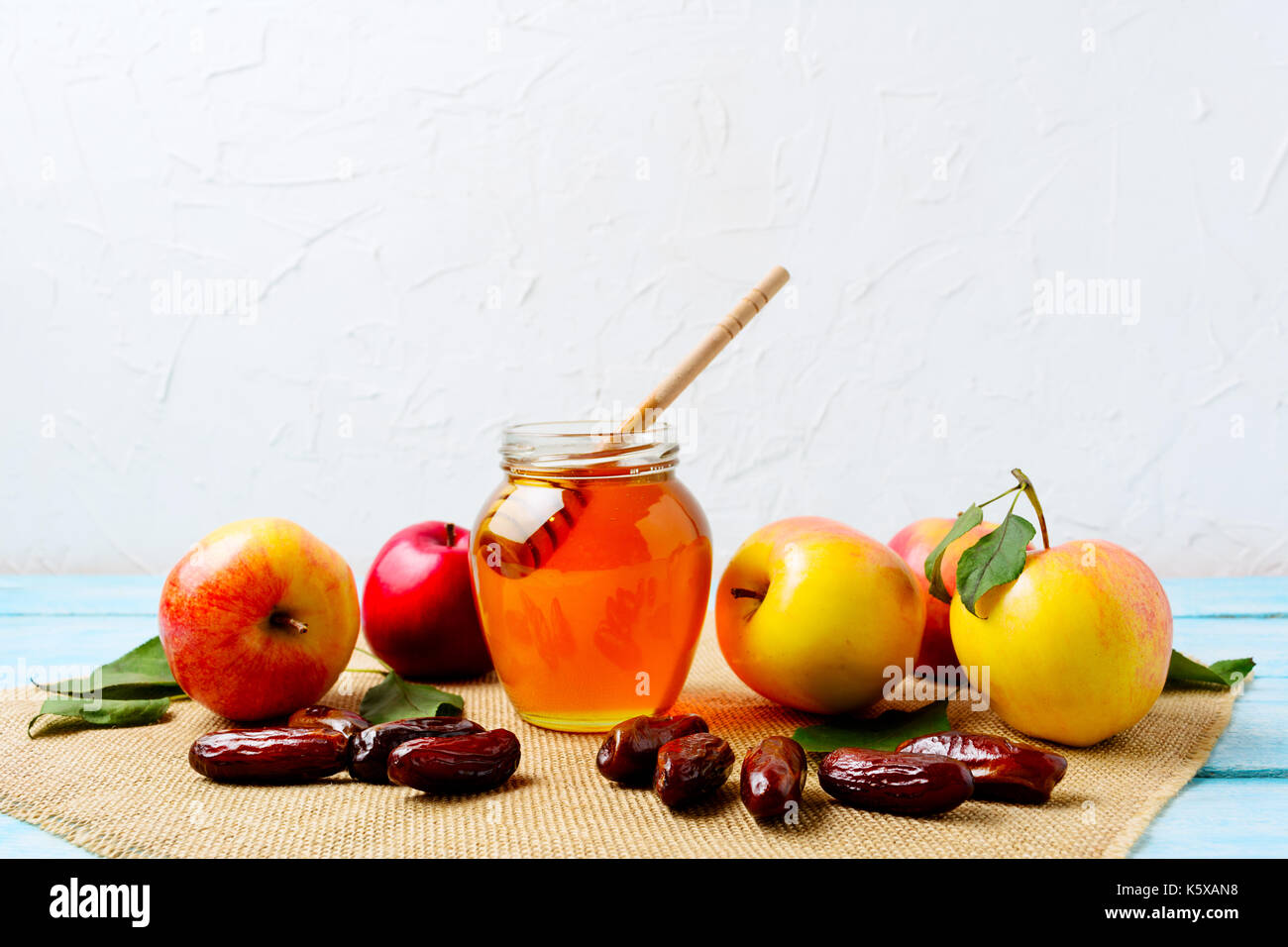 Vaso di miele, date e mele fresche con foglie verdi sulla tela assorbente. Rosh hashanah concetto. jewesh nuovo anno simboli. Foto Stock