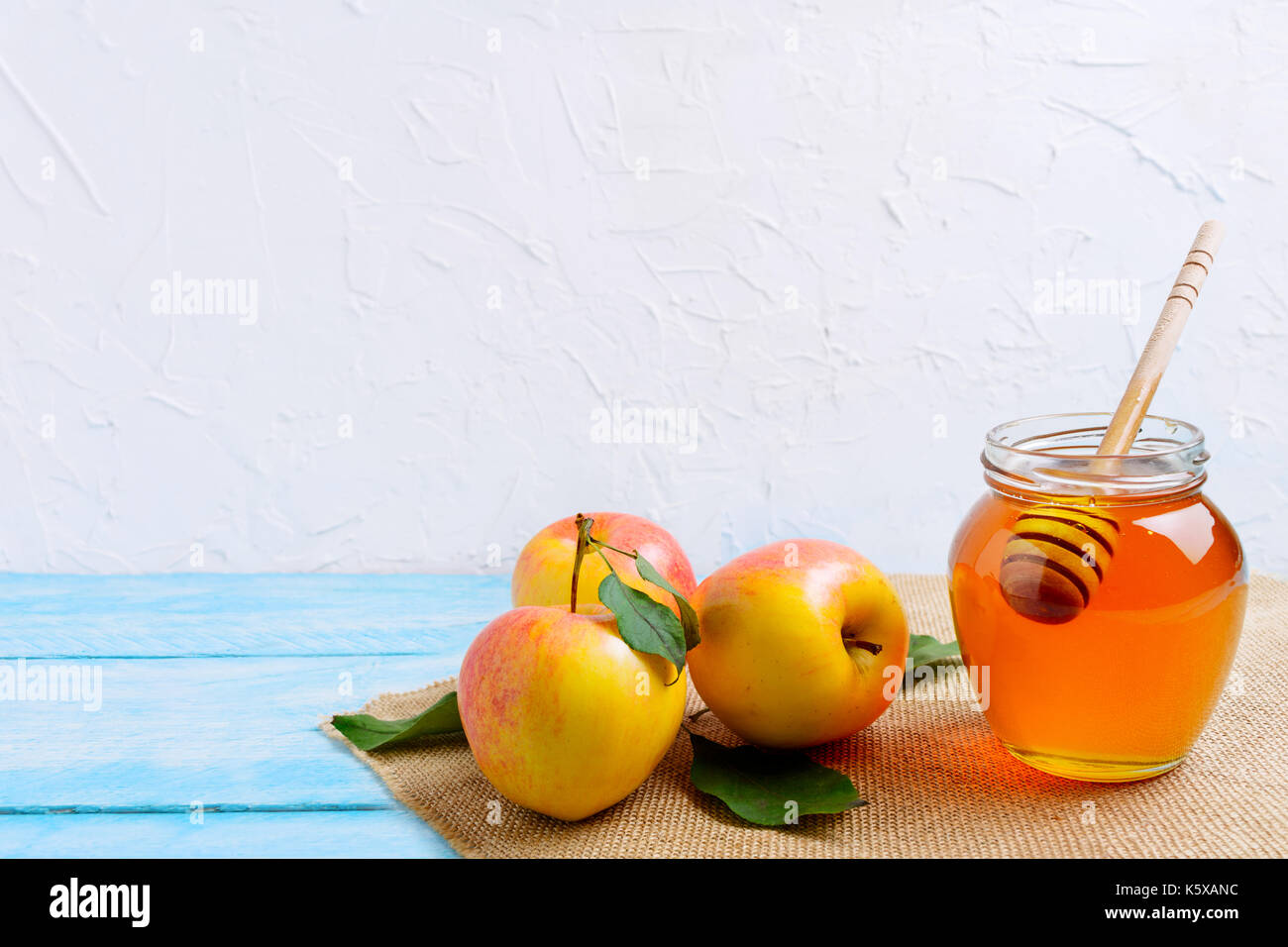 Il miele vasetto in vetro con bilanciere e mele su sfondo bianco, copia spazio. Rosh hashanah concetto. jewesh nuovo anno simboli. Foto Stock