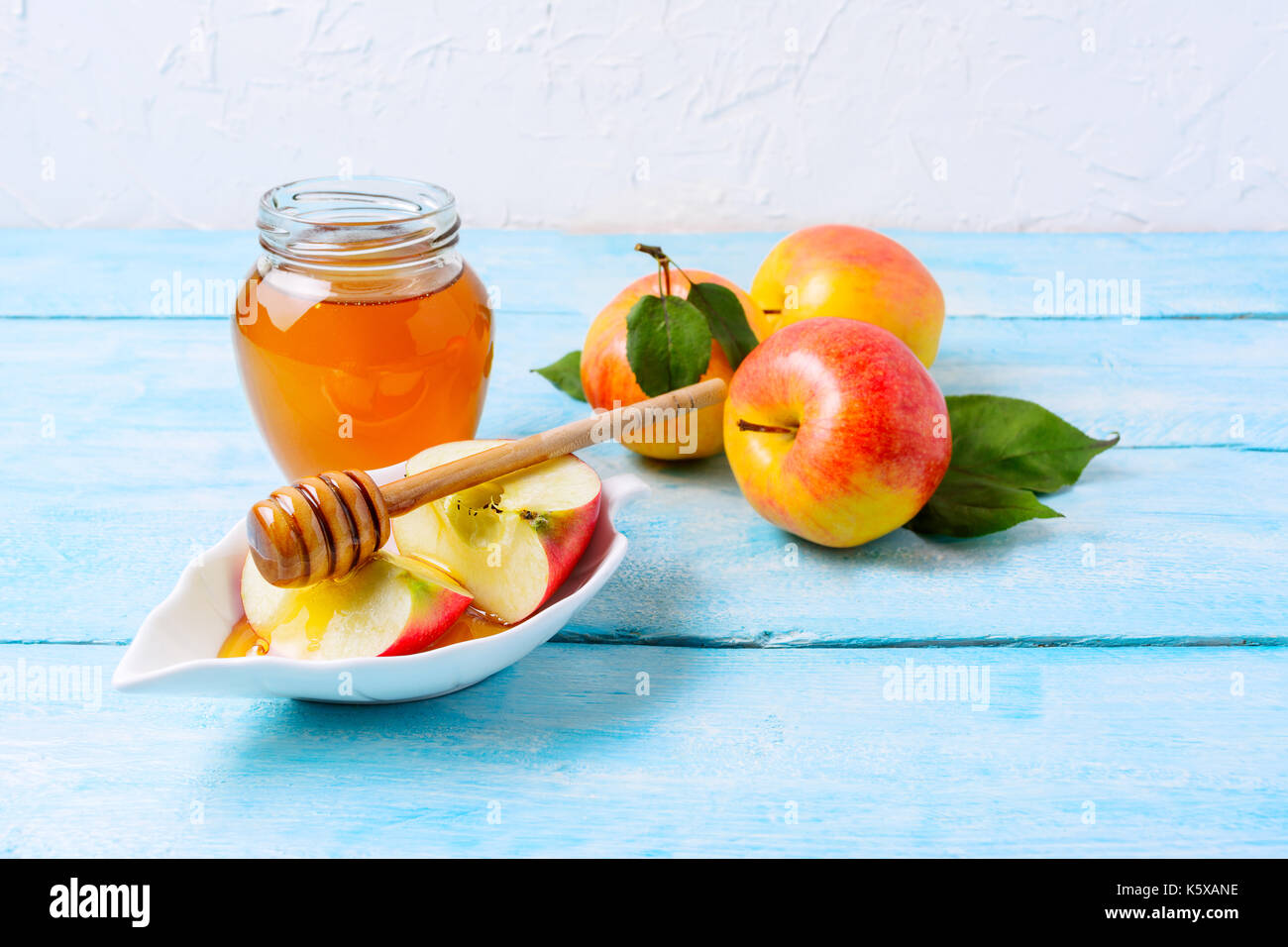 Vasetto di miele e fette di mela con bilanciere su blu sullo sfondo di legno, copia spazio. Rosh hashanah concetto. jewesh nuovo anno simboli. Foto Stock