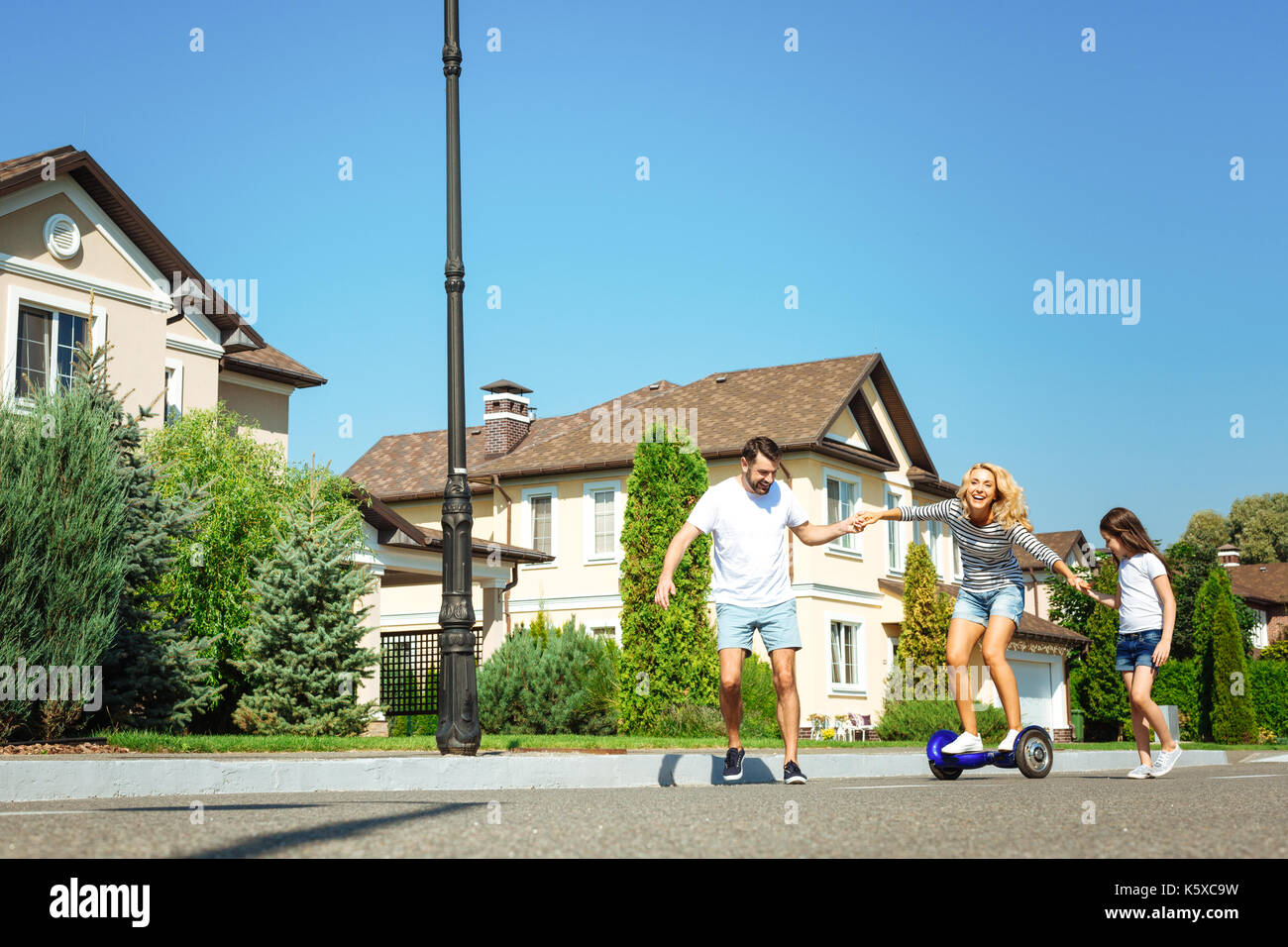 Cura l'uomo e la figlia aiutando madre hoverboard di equitazione Foto Stock