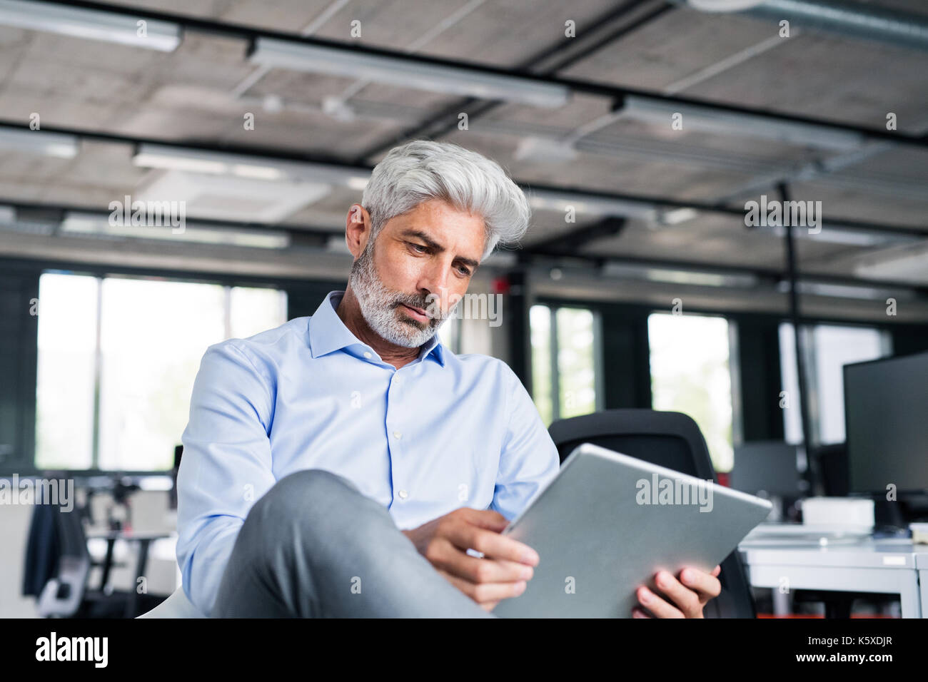 Imprenditore maturo con la compressa in ufficio. Foto Stock