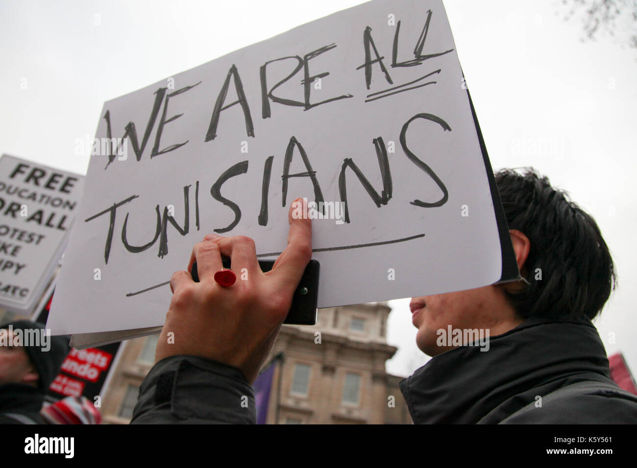 Un pro-Tuinsia protester detiene una targhetta "Siamo tutti tunisini' durante lo studente tasse protesta nel centro di Londra, Regno Unito. Foto Stock