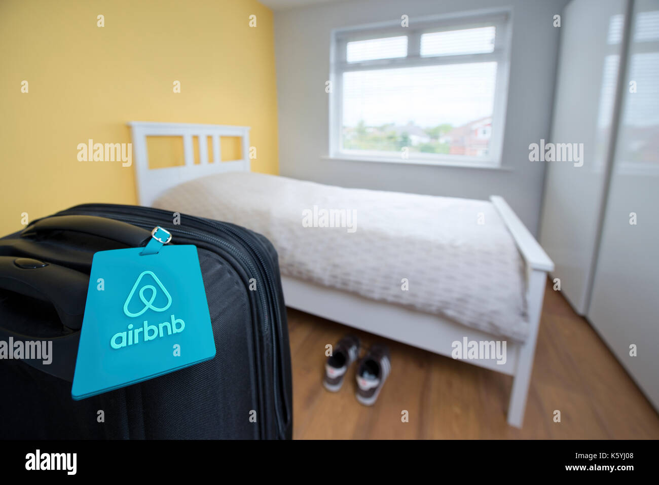 Un marchio Airbnb etichetta bagaglio legato ad una valigia in una camera da letto disponibile in affitto come parte di un appartamento Airbnb. Foto Stock