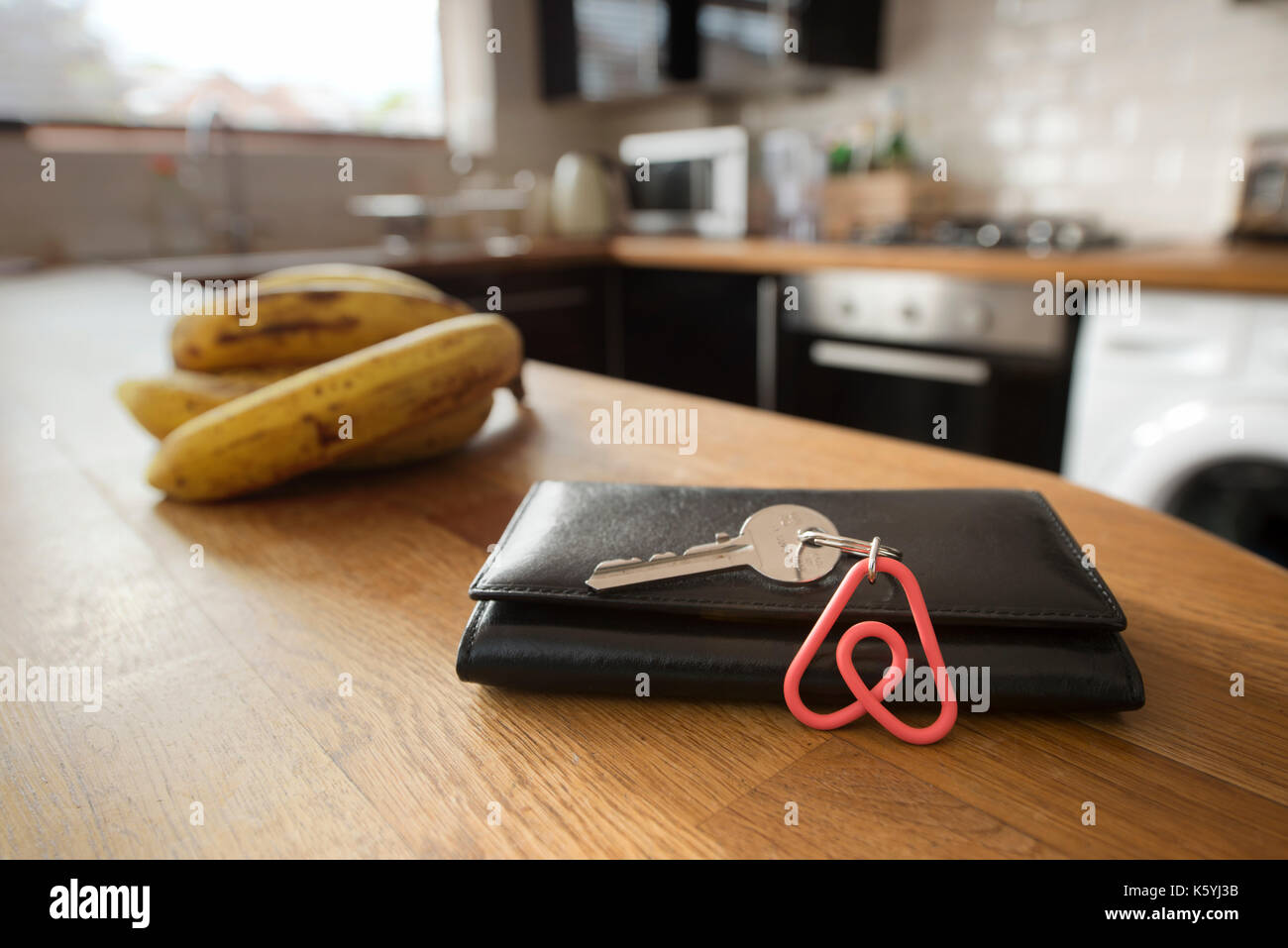 Un portachiavi Airbnb appoggia contro un portafogli nella cucina di un appartamento Airbnb disponibile a noleggio da parte degli ospiti. Foto Stock