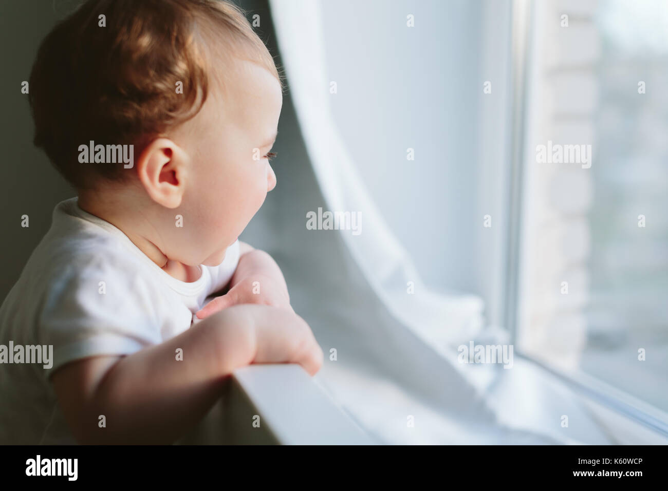 Piccolo bambino tiene sul letto e si guarda da qualche parte. Foto Stock