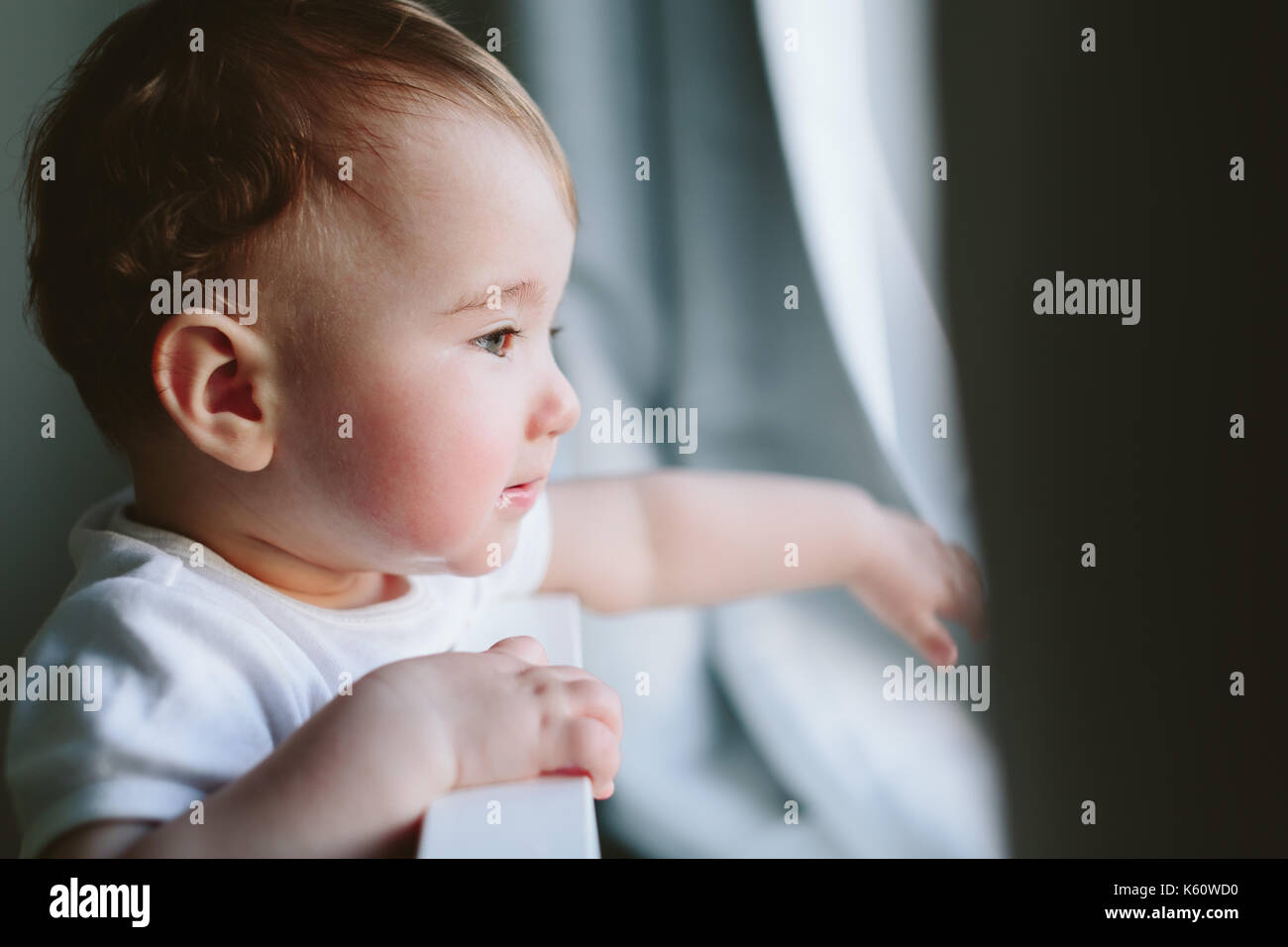 Piccolo bambino tiene sul letto e si guarda da qualche parte. Foto Stock