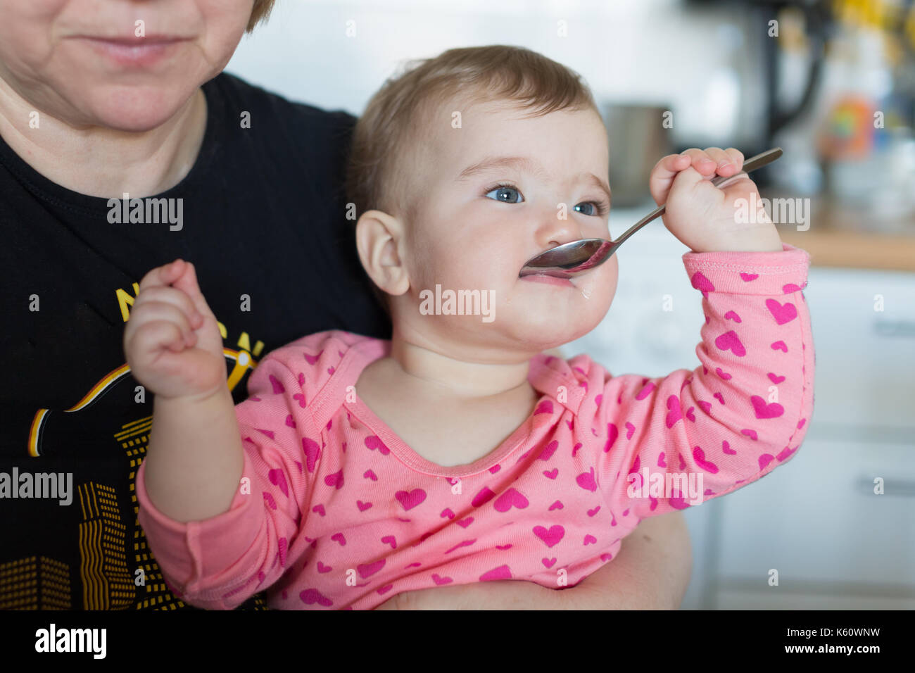 Un bambino piccolo con un cucchiaio in bocca. Foto Stock