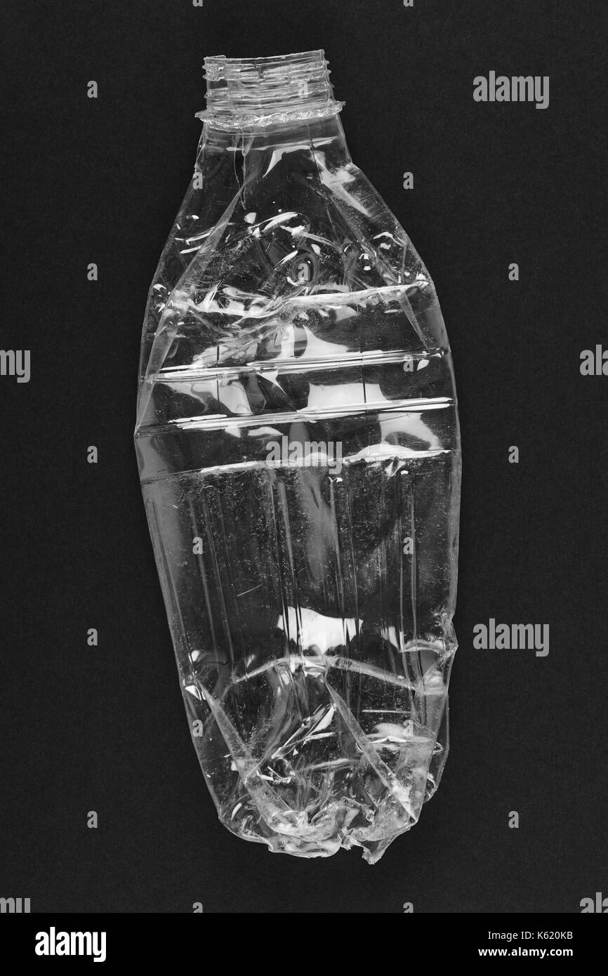 Schiacciato la bottiglia di plastica con sfondo nero di rifiuti riciclati verticale. Foto Stock