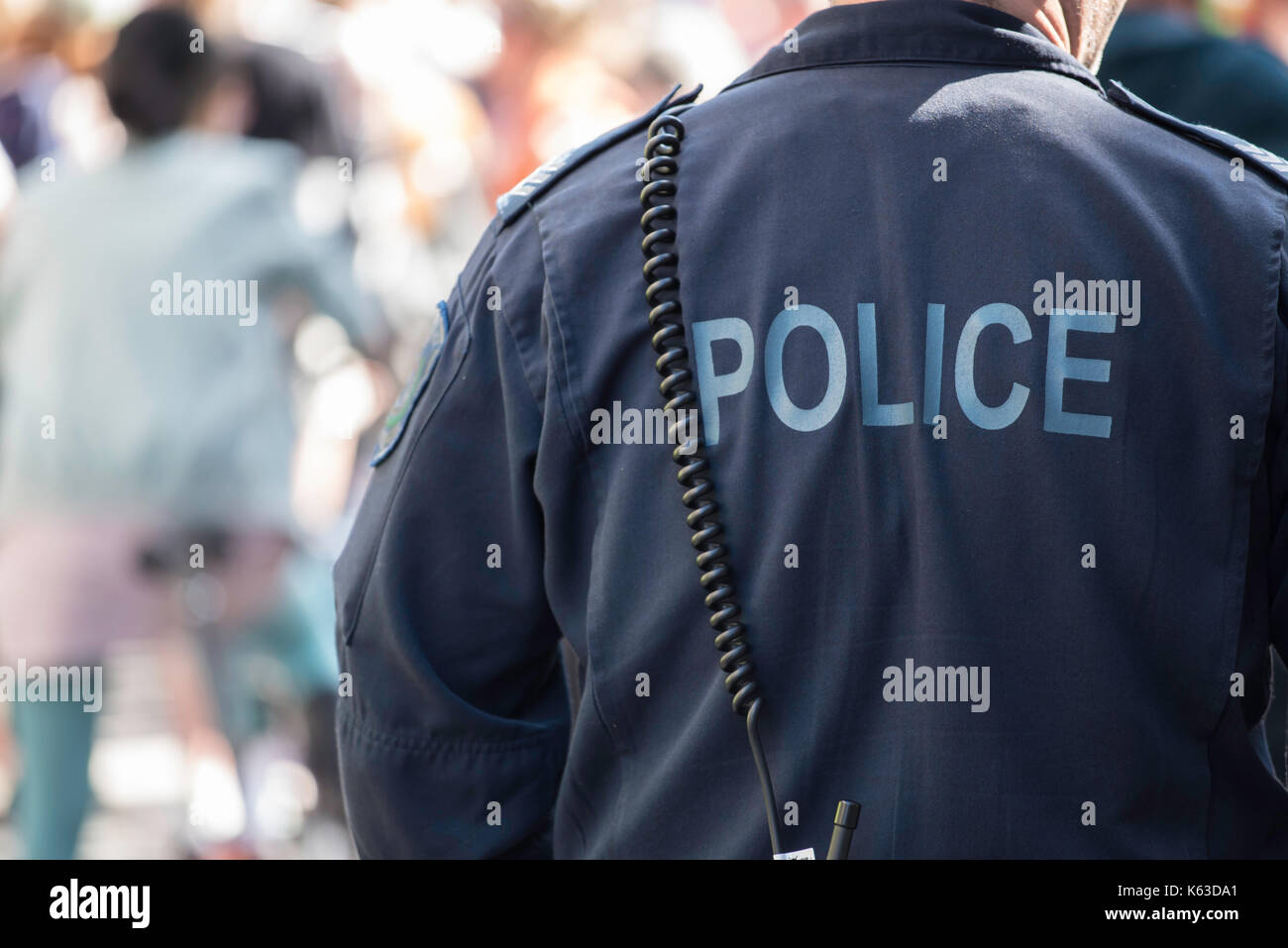 Un'immagine del retro di un poliziotto in uniforme sul dovere di indossare tute blu Foto Stock