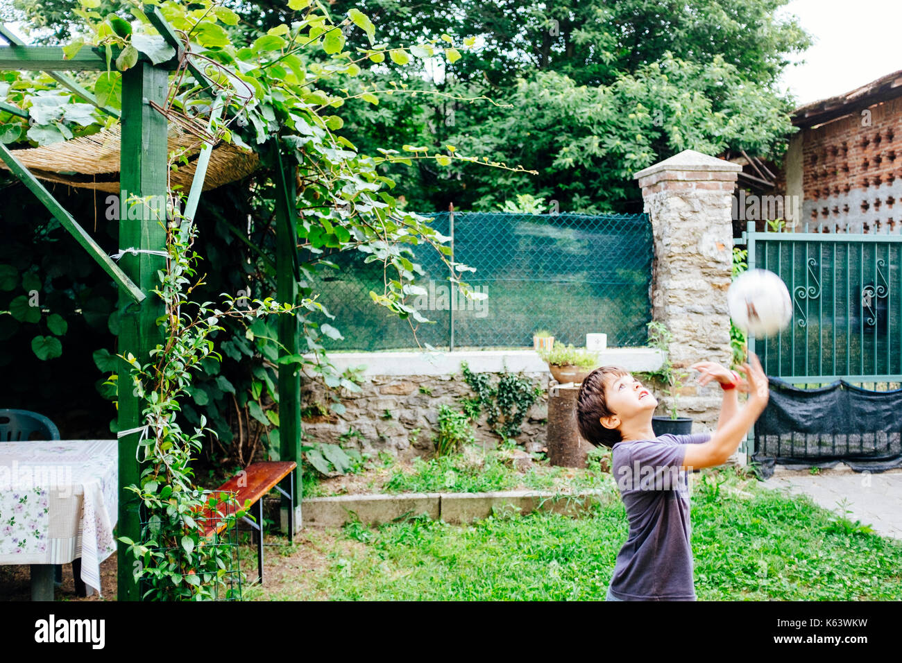 Il bambino gioca palla in giardino Foto Stock