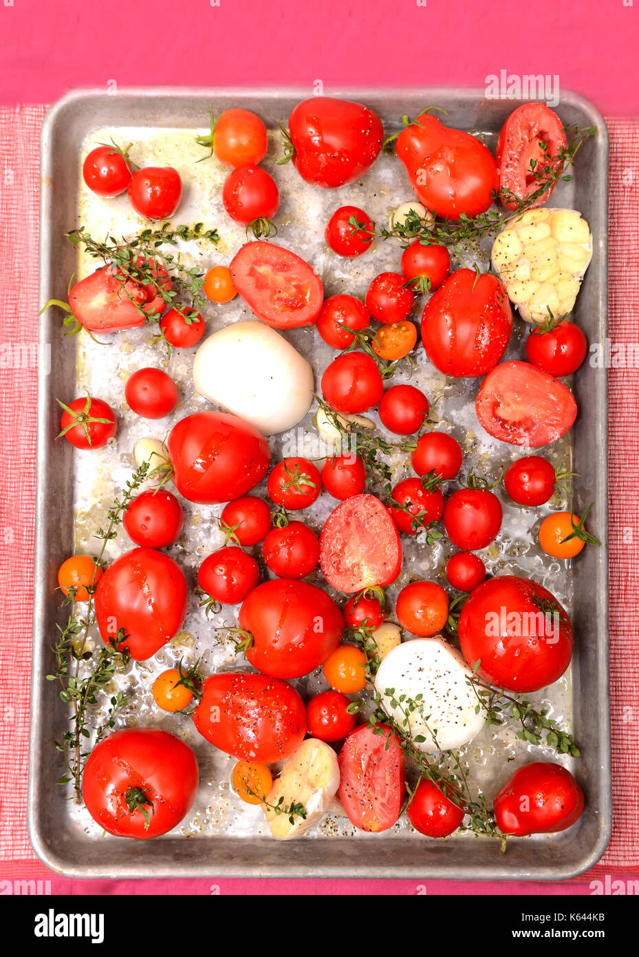 Pomodori freschi, aglio, cipolle e timo in teglia pronti per la tostatura per preparare deliziosi pomodoro e basilico zuppa Foto Stock
