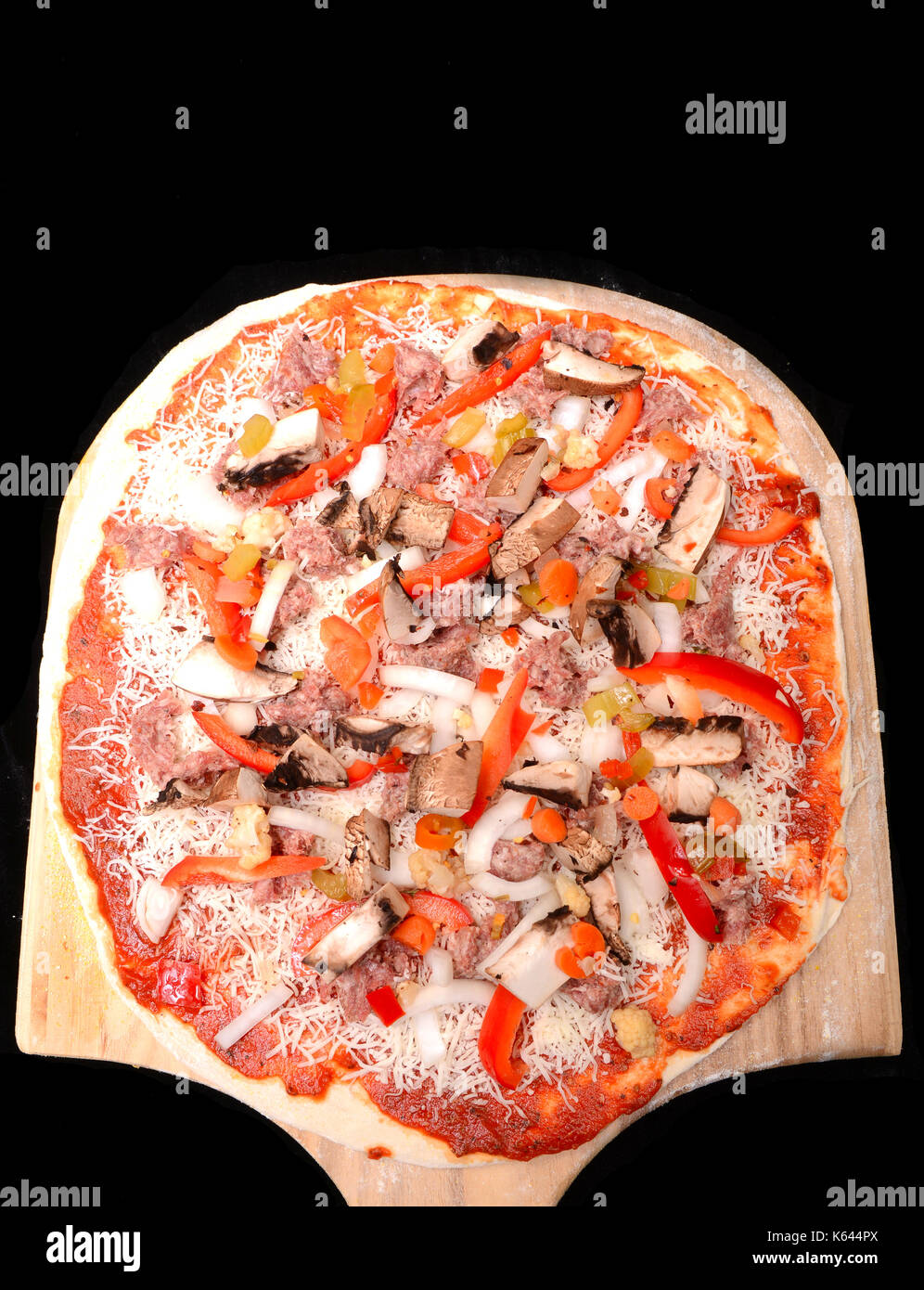 Appena fatta la pizza con le cipolle e peperoni, salsiccia, formaggio e salsa di pomodoro su un peal waithing per essere cotto al forno Foto Stock