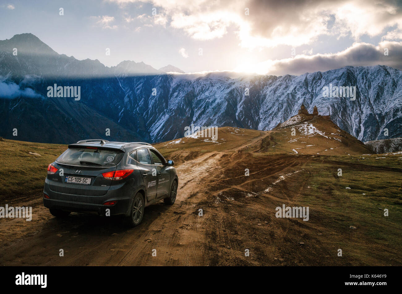 Gergeti, Georgia - 22 ottobre 2016: crossover auto contro il gergeti Trinity Church tsminda sameba, in montagna e sul ghiacciaio di sunrise, stepantsminda, Foto Stock