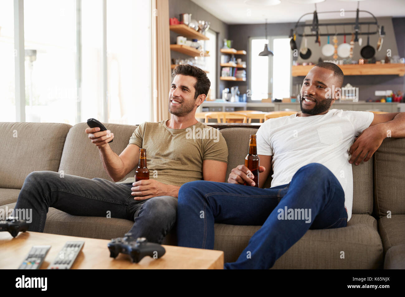 Due amici maschi seduti sul divano e guardare lo sport in TV Foto Stock