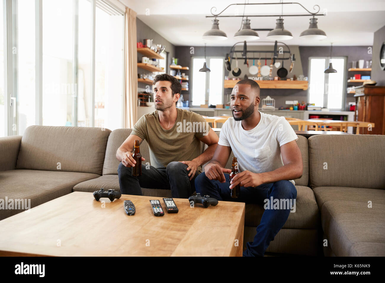 Due amici maschi seduti sul divano e guardare lo sport in TV Foto Stock