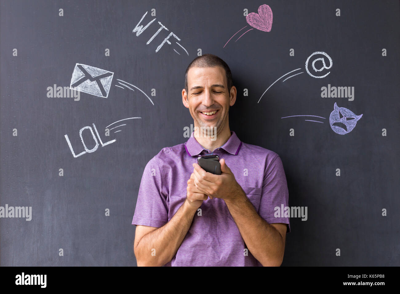 Concetto di social media chat. Singola bianco uomo adulto in piedi di fronte a una lavagna usando il suo smart phone. Foto Stock