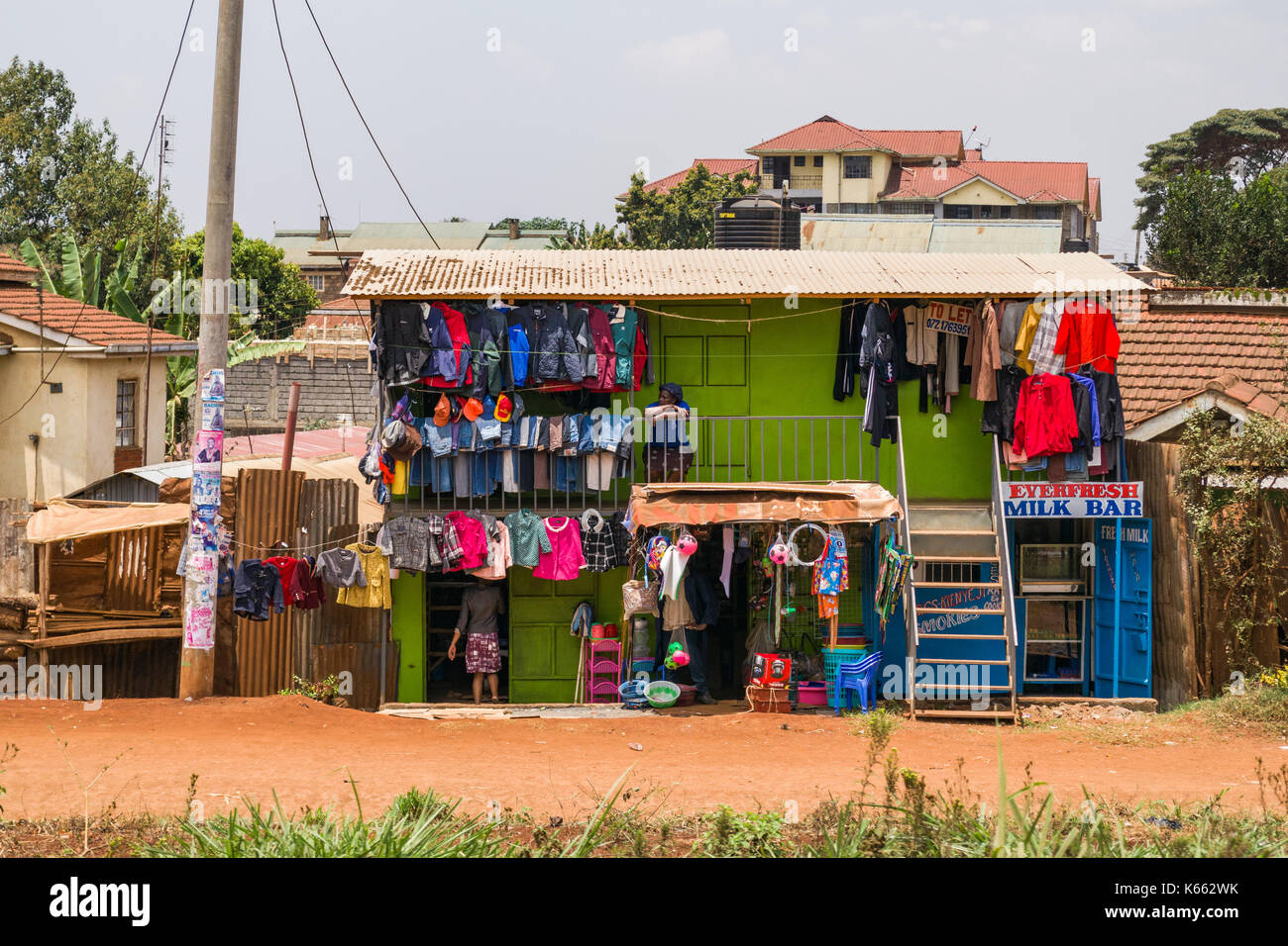 Un piccolo edificio con negozi di abbigliamento e vestiti appesi all'esterno, Kenya Foto Stock