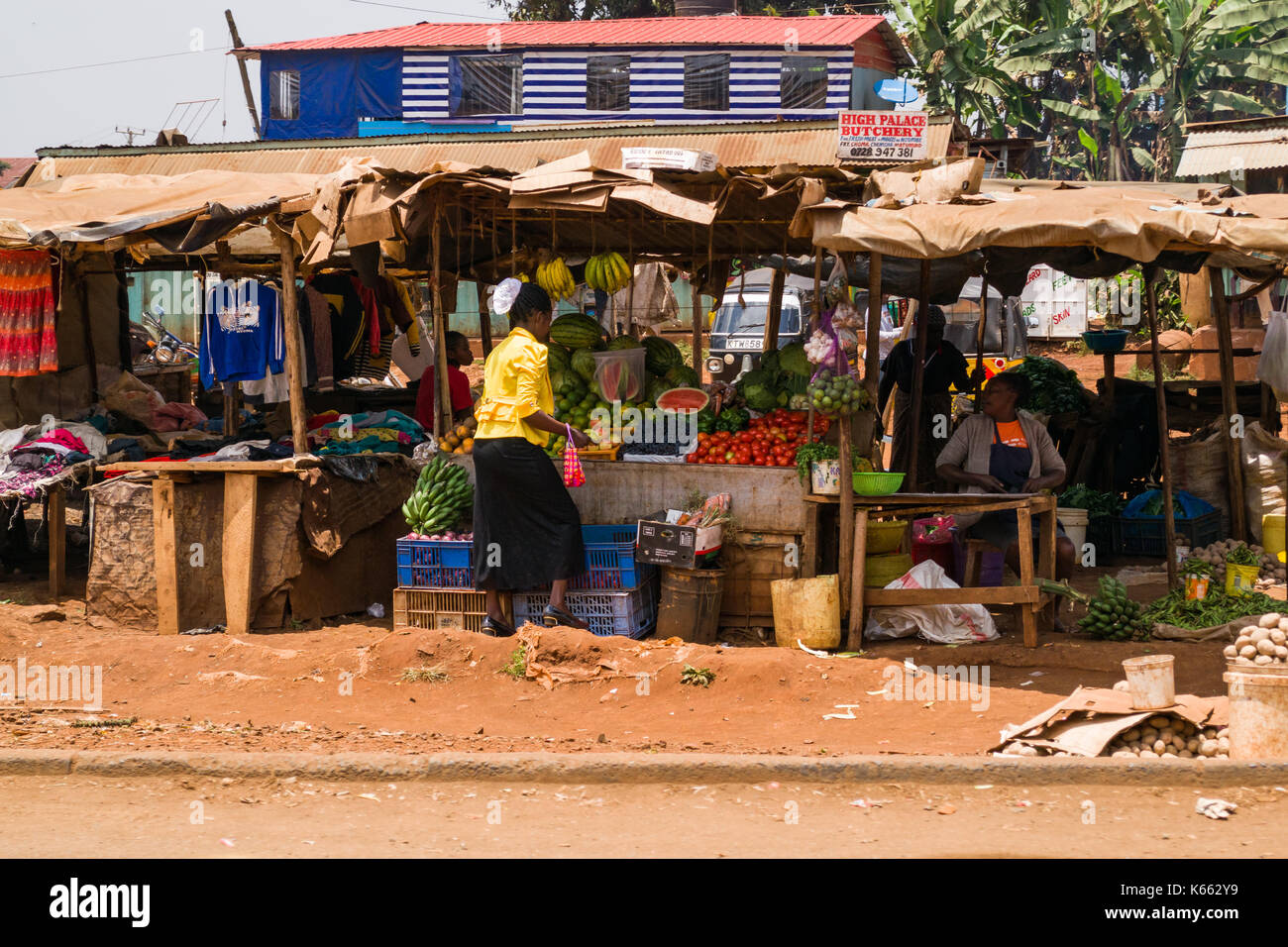 Mercato di frutta e verdura bancarelle con gente seduta e la navigazione, Kenya Foto Stock
