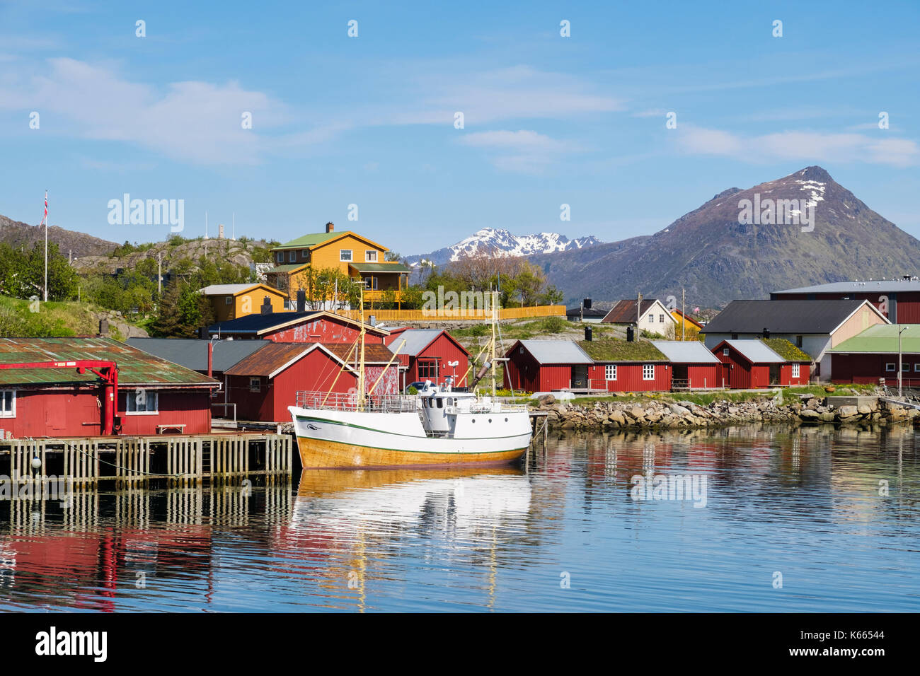 Barca ormeggiata in porto con tipici norvegesi Rorbu capanne nel villaggio di pescatori. Ballstad, Vestvågøya isola, isole Lofoten, Nordland, Norvegia Foto Stock