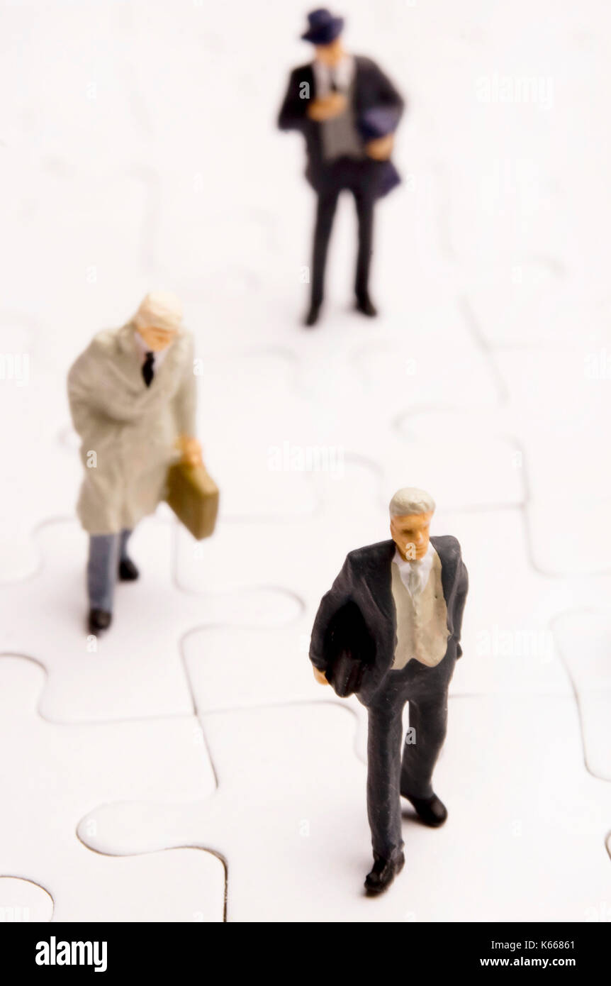 Business figurine in miniatura su puzzle Foto Stock