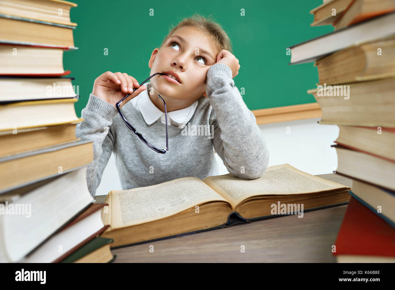 Trasognata School girl, guardando verso l'alto. foto della bambina con il libro aperto, fantasticando o pensando a qualcosa. Il concetto di istruzione Foto Stock
